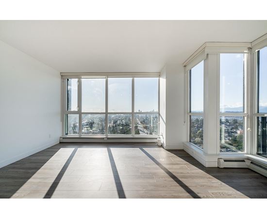 A large empty room with a view of the city through the windows.