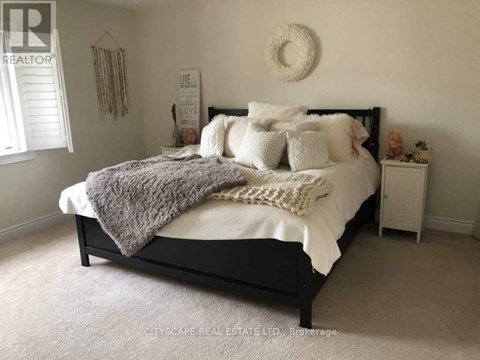 A bedroom with a large bed and a wreath on the wall.