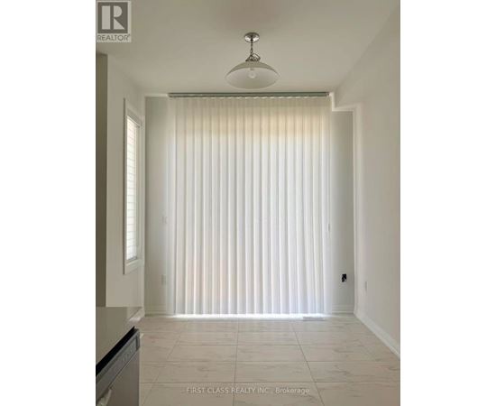 A white room with a light on the ceiling and a window with blinds.