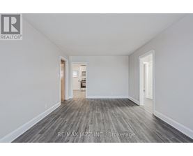 A spacious room with wood flooring and white walls, ready for brokerage.