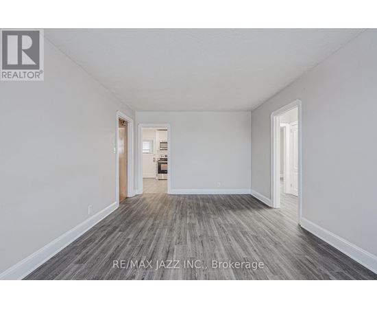 A spacious room with wood flooring and white walls, ready for brokerage.