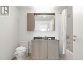 A bathroom with a toilet, sink, and mirror.