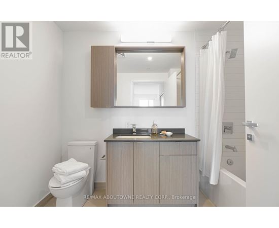 A bathroom with a toilet, sink, and mirror.