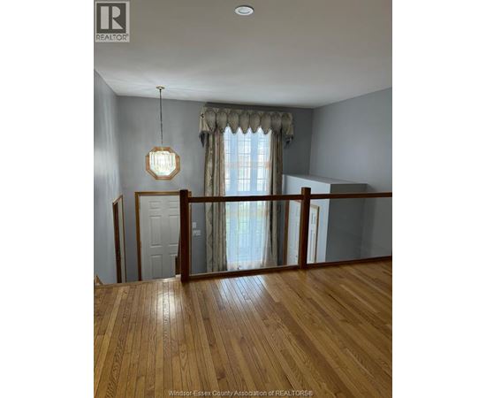 A wooden floor in a room with a window and a chandelier.