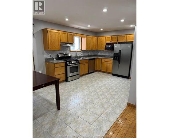 A kitchen with wooden cabinets and a tile floor.