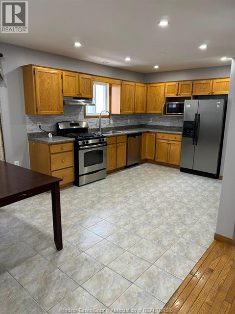 A kitchen with wooden cabinets and a tile floor.