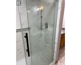A glass shower stall with a black handle.