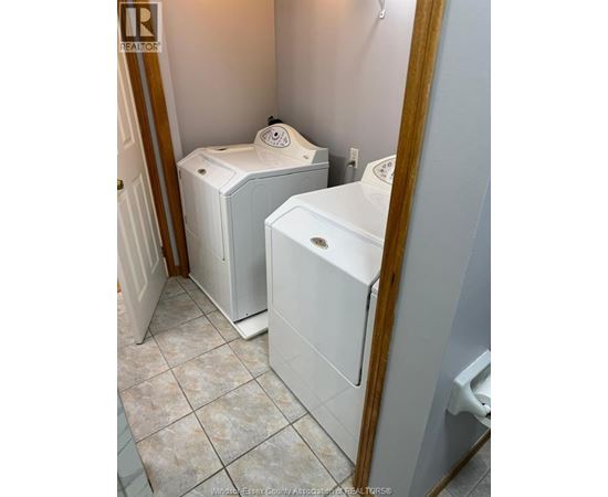A bathroom with a toilet, a washing machine, and a dryer.