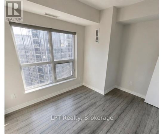 A room with a large window and wooden flooring.