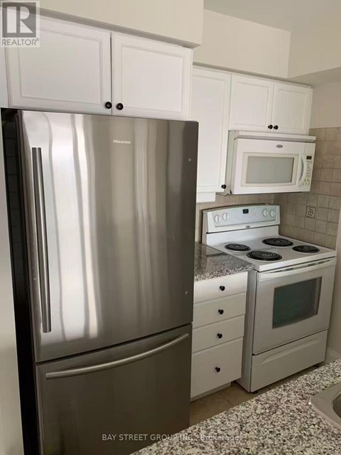 A kitchen with a stainless steel refrigerator and a white microwave oven.