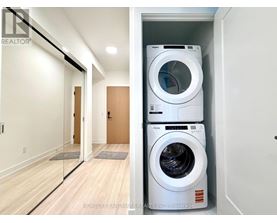 A white washing machine is stacked on top of another white washing machine in a small laundry room.