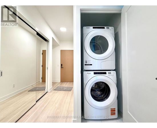 A white washing machine is stacked on top of another white washing machine in a small laundry room.