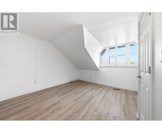 A white room with a window and wooden flooring.