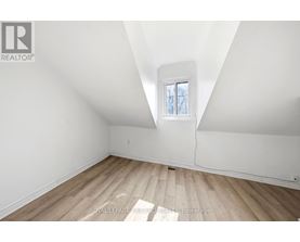 A white room with wooden flooring and a skylight window.