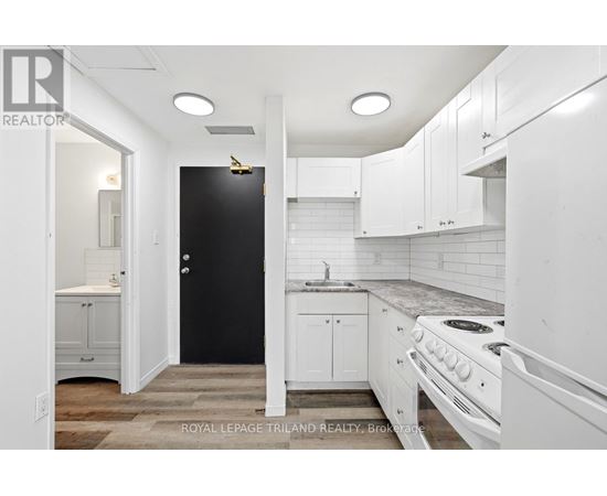 A white kitchen with a black door and a stove top oven.