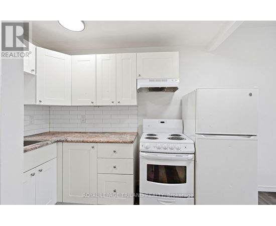 A white kitchen with a stove and refrigerator.