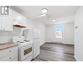 A kitchen with white appliances and wooden floors.