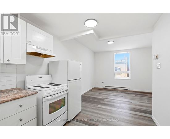 A kitchen with white appliances and wooden floors.