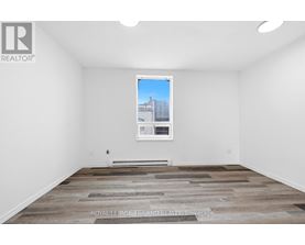 A room with a wooden floor and a picture of a building on the wall.