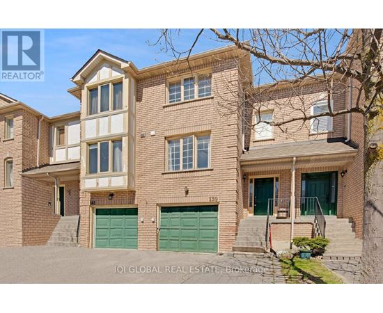 A two-story brick house with a green garage door is for sale.