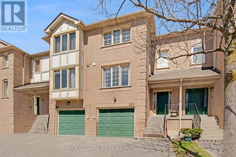 A two-story brick house with a green garage door is for sale.