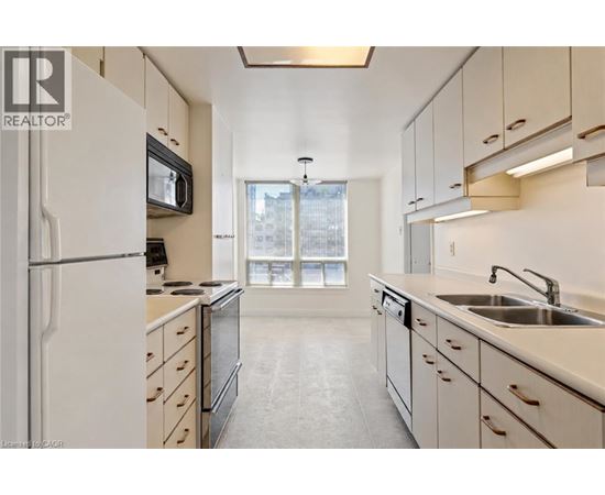 A kitchen with white cabinets and a black microwave.
