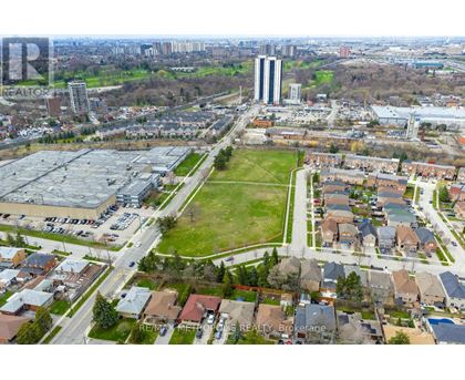 A bird's eye view of a residential area with houses, a park, and a large building in the distance.