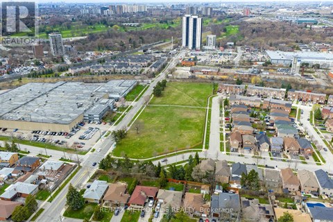 A bird's eye view of a residential area with houses, a park, and a large building in the distance.