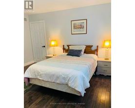A bedroom with a bed, two lamps, and a picture on the wall.