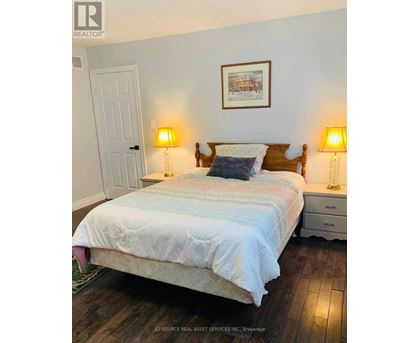 A bedroom with a bed, two lamps, and a picture on the wall.