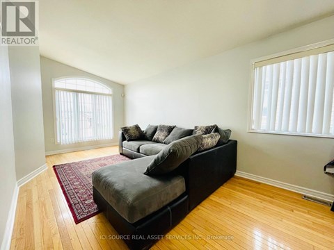A living room with a grey couch and a red rug.
