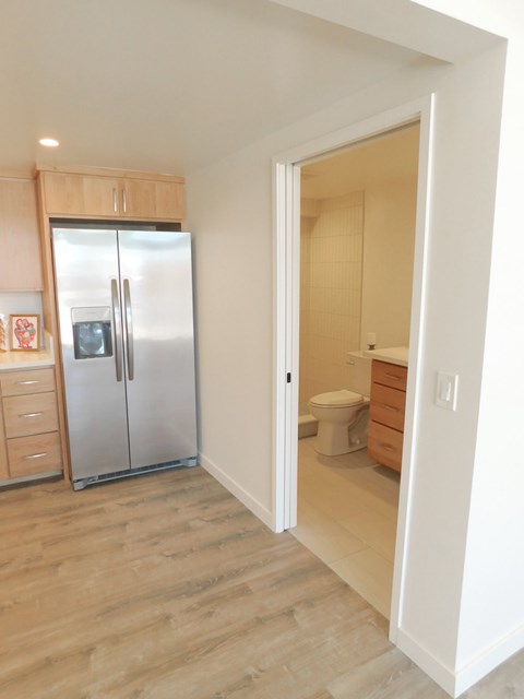A kitchen with a refrigerator, toilet, and sink.