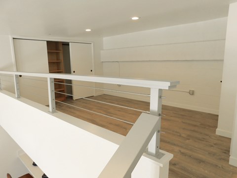 A white balcony with a railing and a wooden floor.