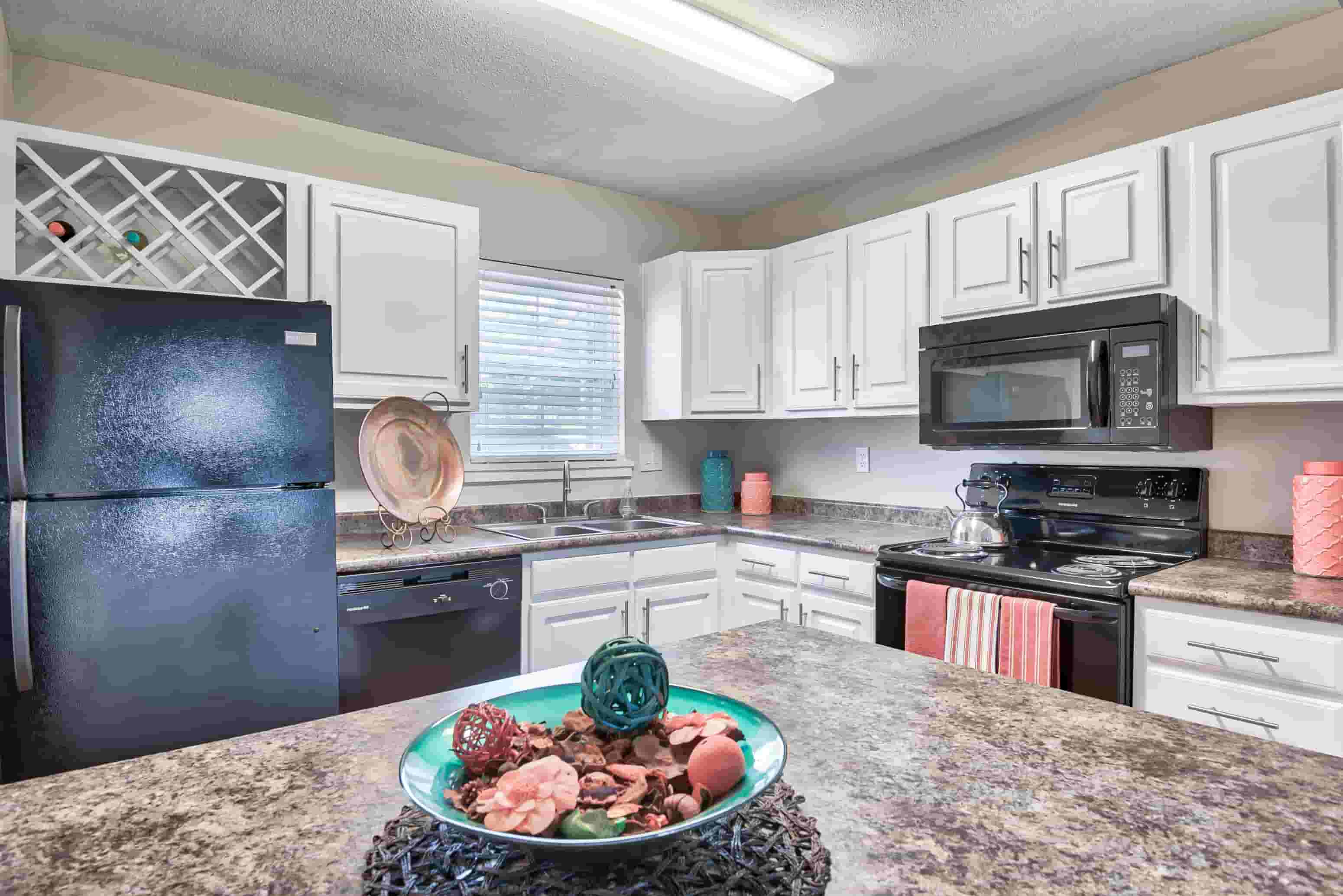 A kitchen with a black refrigerator and a decorative plate on the counter.