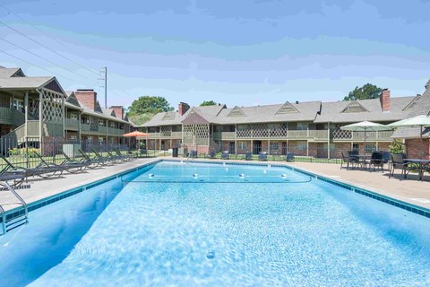 A large swimming pool in front of a building with a fence around it.