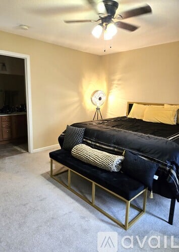 A bedroom with a black bed and a ceiling fan.