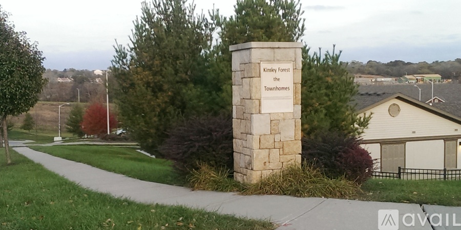 A stone pillar with the inscription "Kinley Forest the Towers" stands in a grassy area.