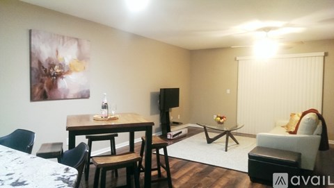 A living room with a couch, a table, a television, and a painting on the wall.