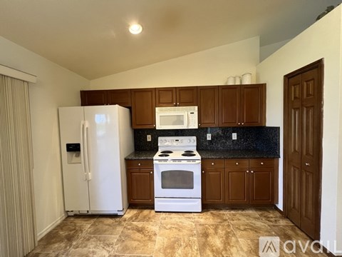 A kitchen with brown cabinets and a white fridge.