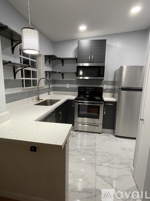 A kitchen with a white counter top and stainless steel appliances.