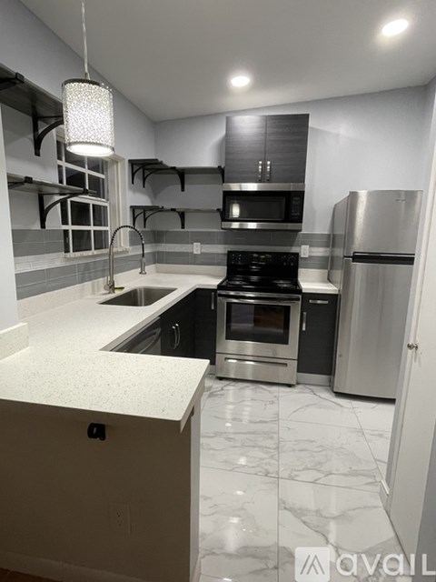 A kitchen with a white counter top and stainless steel appliances.