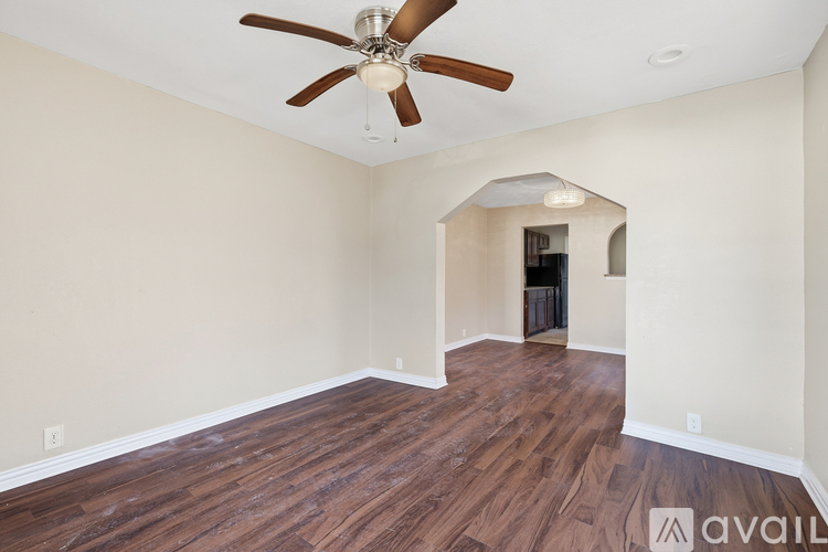 A room with a ceiling fan and wooden flooring.