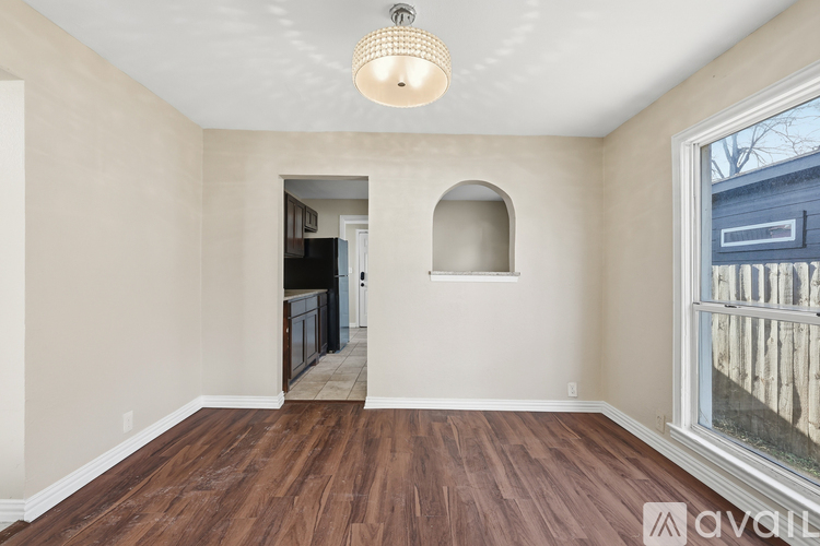 A room with wooden floors and a window showing a building outside.