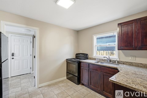 A kitchen with a white door, black oven, and a window with a view of the water.