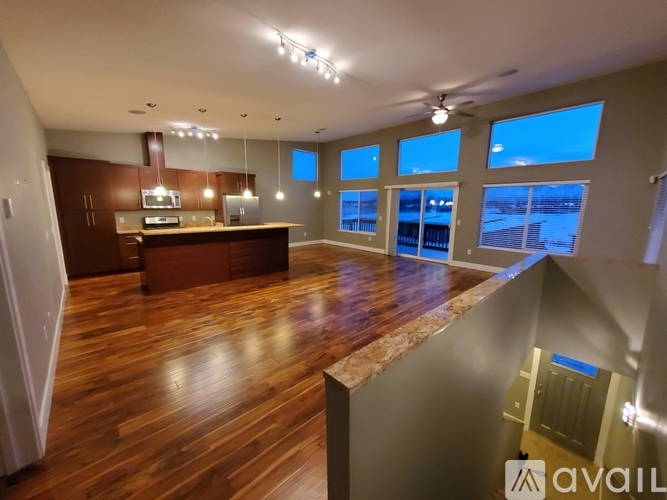 A spacious room with wooden floors and a large window overlooking a body of water.