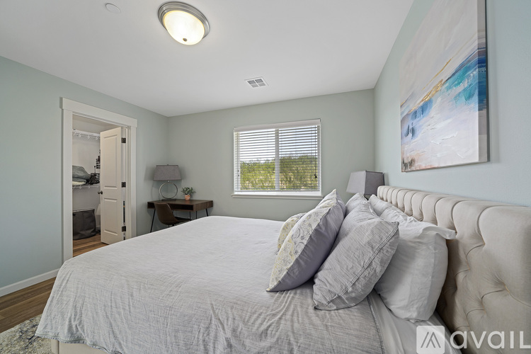 A bedroom with a large bed and a painting on the wall.