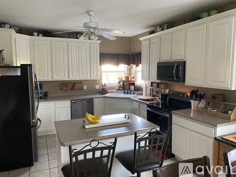 A kitchen with white cabinets and a black refrigerator.