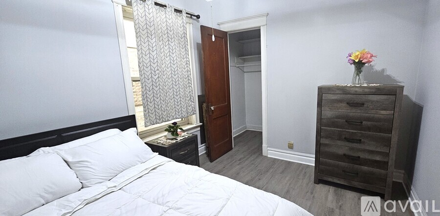 A bedroom with a bed, dresser, and window.
