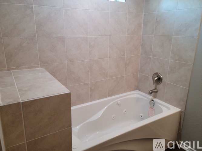 A white bathtub with a shower head in a tiled bathroom.