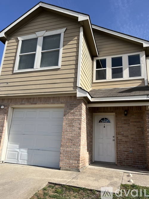 A house with a white garage door and a brick wall.